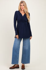 woman wearing a navy long sleeve wrap top with a gathered bodice and blue wide-leg jeans