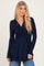 woman wearing a navy blue long sleeve wrap top with a gathered waist and a flowy hemline