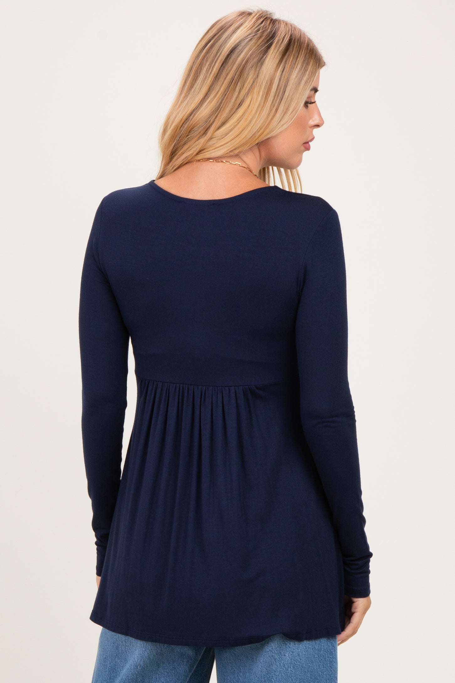 woman wearing a navy long sleeve top with a gathered waist and a relaxed fit, shown from the back