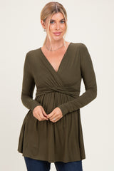 woman wearing an olive green long sleeve wrap top with a knot detail and a flowing silhouette
