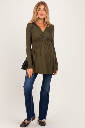 woman wearing an olive green long sleeve maternity top with a wrapped front and a baby bump, paired with blue flared jeans