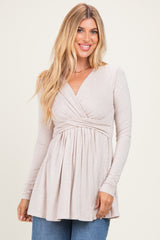woman wearing a light beige long sleeve wrap top with pleated details and a relaxed fit