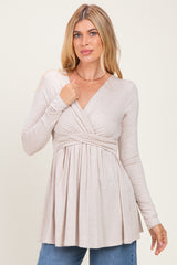 woman wearing a beige long sleeve top with a wrap front and gathered waist, styled with blue jeans