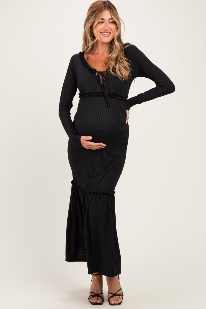 woman wearing a black ribbed maternity dress with long sleeves and a ruffled hem, showcasing her baby bump
