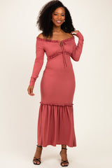 woman wearing a rusty pink off-the-shoulder ribbed maxi dress with a tie-front detail and ruffled hem