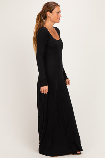 woman wearing a long sleeve black maxi dress with a scoop neckline and flowing skirt