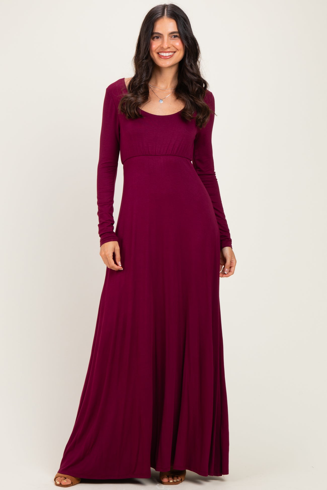 woman wearing a burgundy long sleeve maxi dress with a fitted bodice and a flowing skirt