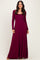 woman wearing a burgundy long sleeve maxi dress with a fitted bodice and a flowing skirt