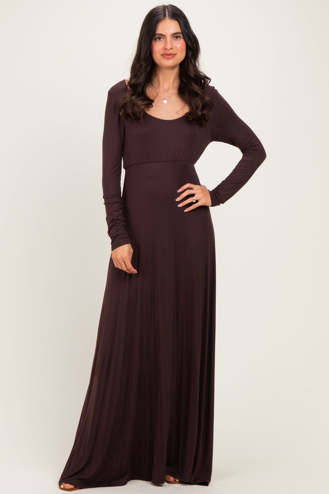 woman wearing a long sleeve dark brown maxi dress with a fitted bodice and flowing skirt