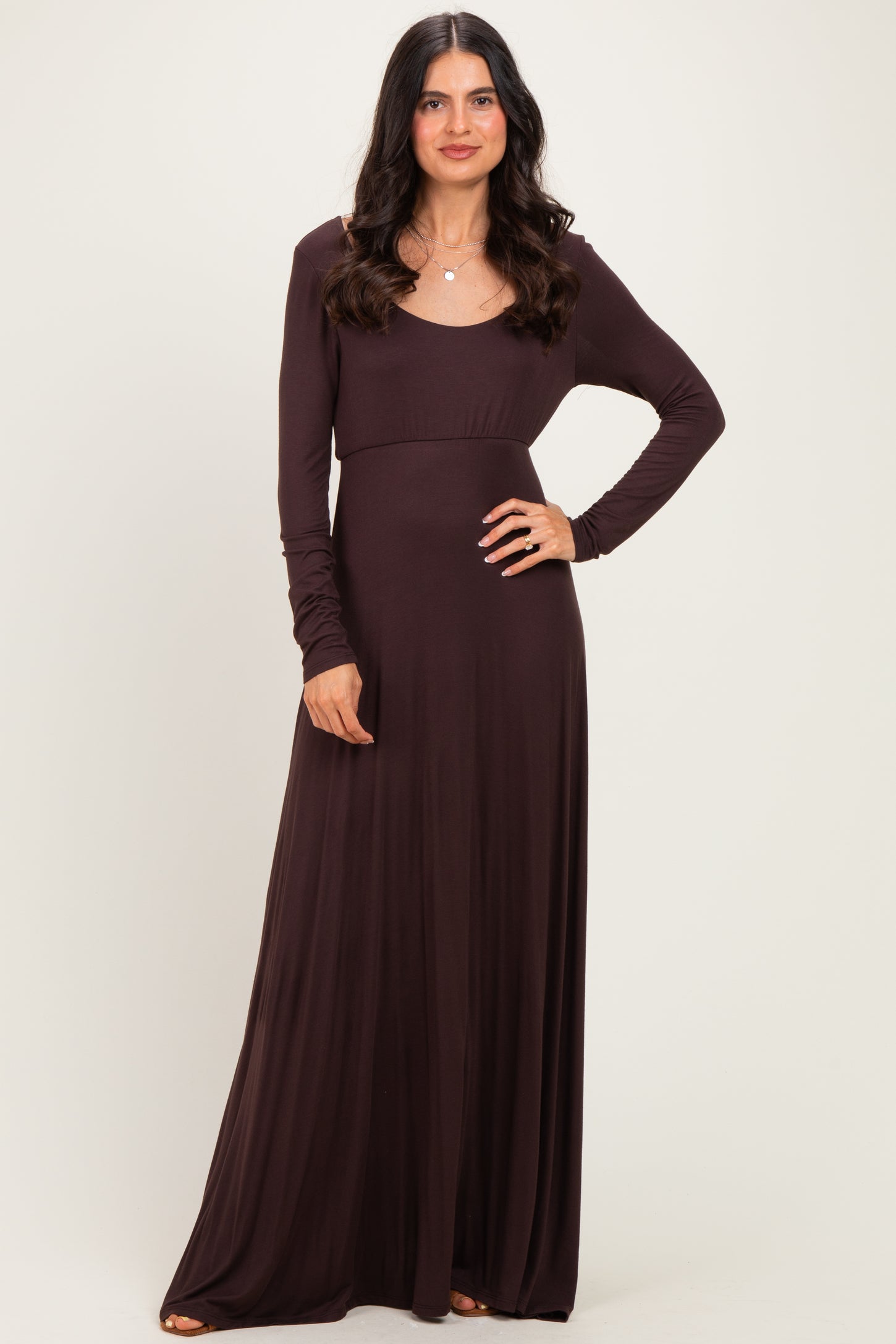 woman wearing a long sleeve dark brown maxi dress with a fitted bodice and flowing skirt