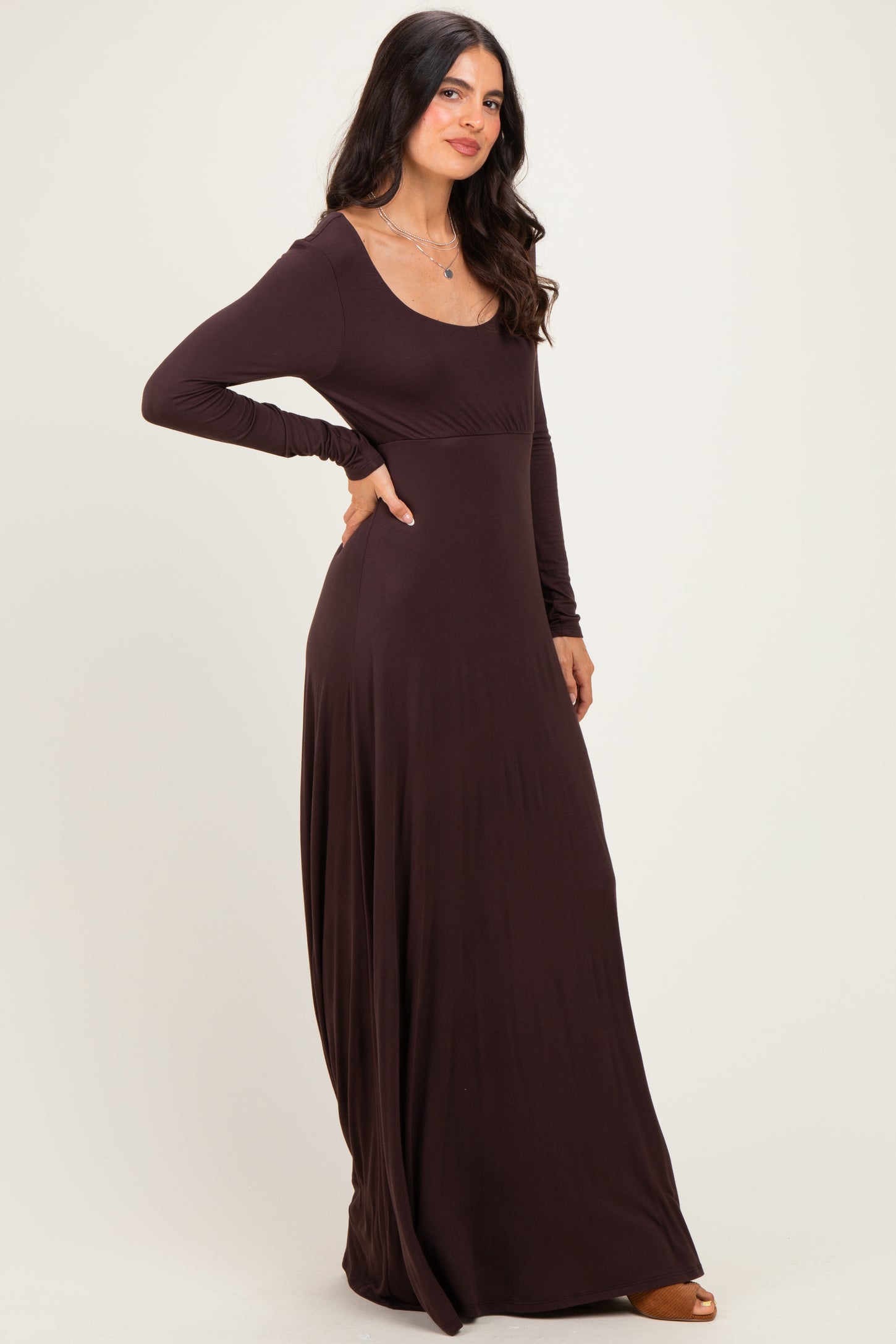 woman wearing a brown long sleeve maxi dress with a scoop neckline and flowing silhouette
