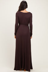 woman wearing a long sleeve dark brown maxi dress with a fitted waist and flowing skirt, seen from the back