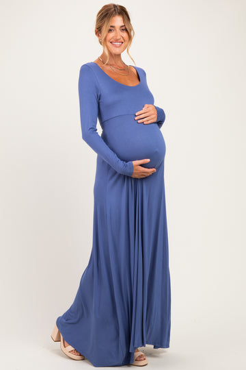 woman wearing a long sleeve blue maternity maxi dress and holding her baby bump