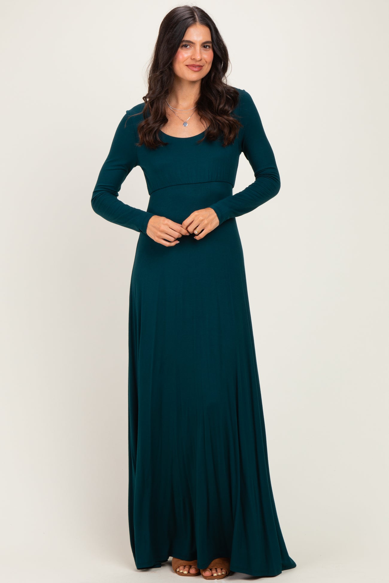 woman wearing a teal long sleeve maxi dress with a fitted bodice and flowy skirt