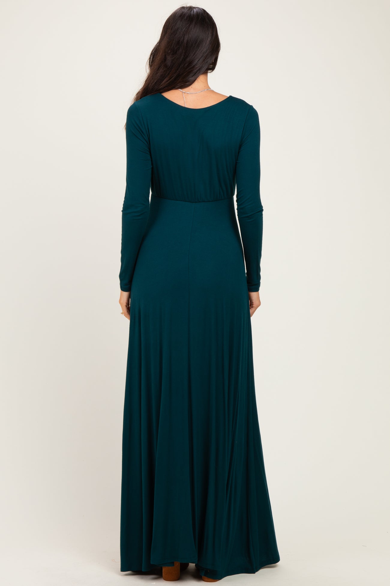 woman wearing a long sleeve dark teal maxi dress, showing the back view and a flowing silhouette
