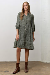 woman wearing an olive green floral button-up dress with puff sleeves and brown ankle boots