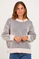 woman wearing a cream and navy striped oversized sweater with ribbed detailing and dropped shoulders