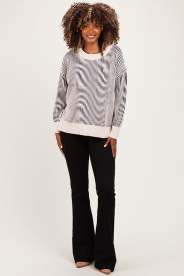 woman wearing a striped black and white maternity sweater with wide sleeves and black flared pants