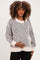 woman wearing a striped maternity sweater in cream and black, holding her baby bump