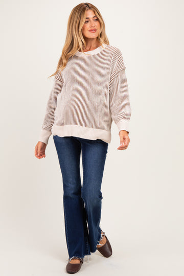 woman wearing a light striped maternity sweater with wide cuffs and bell-bottom jeans, walking confidently