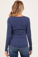woman wearing a navy blue ribbed maternity top, seen from the back, styled with fitted jeans