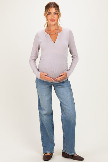 woman wearing a light purple ribbed maternity top and relaxed fit jeans, showing her baby bump