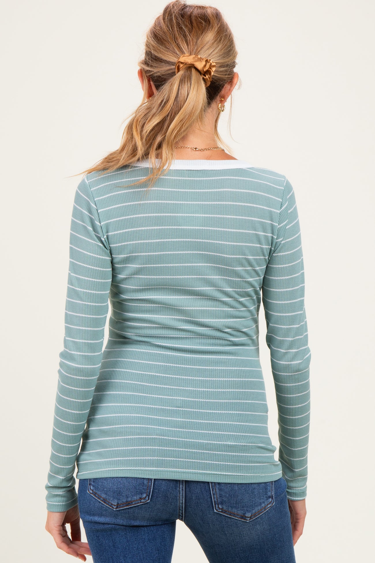 woman wearing a teal and white striped long sleeve maternity top, viewed from the back