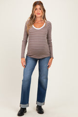 woman wearing a brown and white striped maternity top and blue jeans, showing off her baby bump