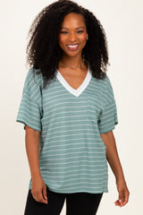 woman wearing a green striped short sleeve top with a v-neck and pocket, smiling at the camera