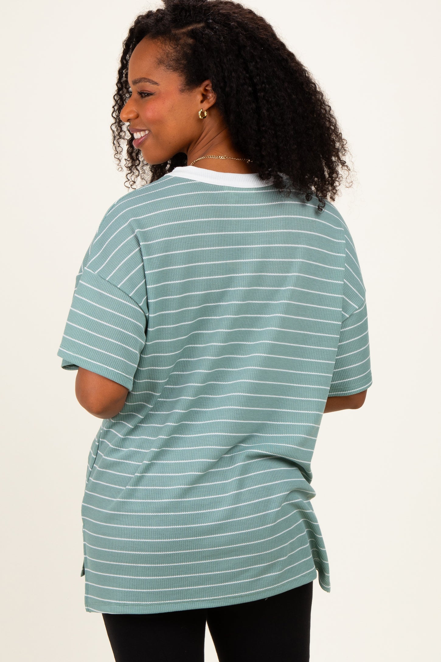 woman wearing a mint green striped oversized t-shirt with short sleeves and a side slit detail