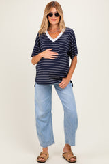 woman wearing a navy and white striped maternity top with a v-neck and holding her baby bump, paired with light blue wide-leg jeans