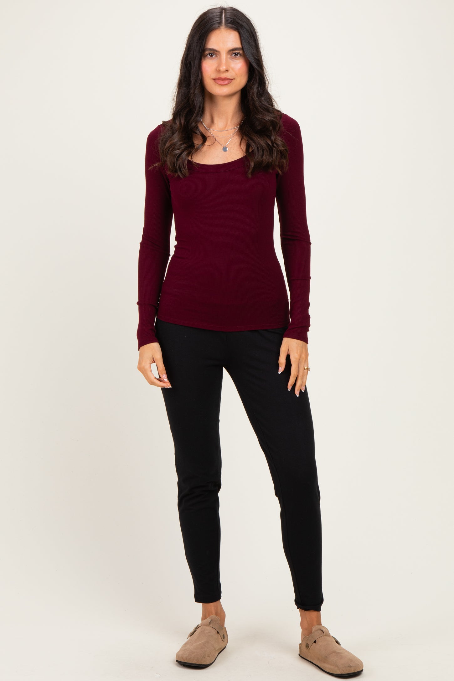 woman wearing a burgundy long sleeve ribbed top and black slim-fit pants