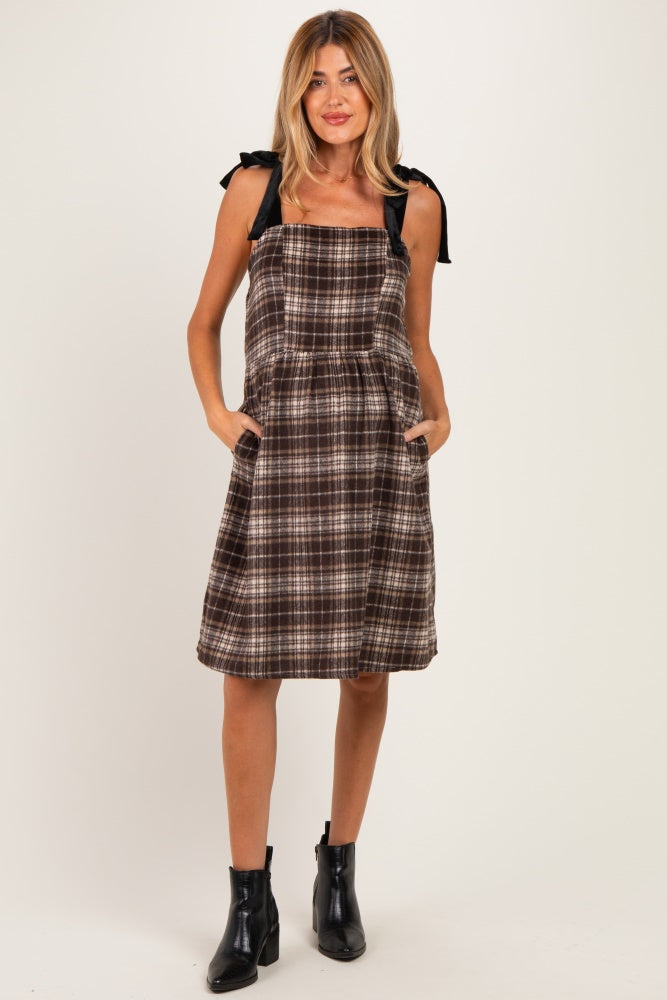 woman wearing a brown plaid maternity dress with tie straps and side pockets