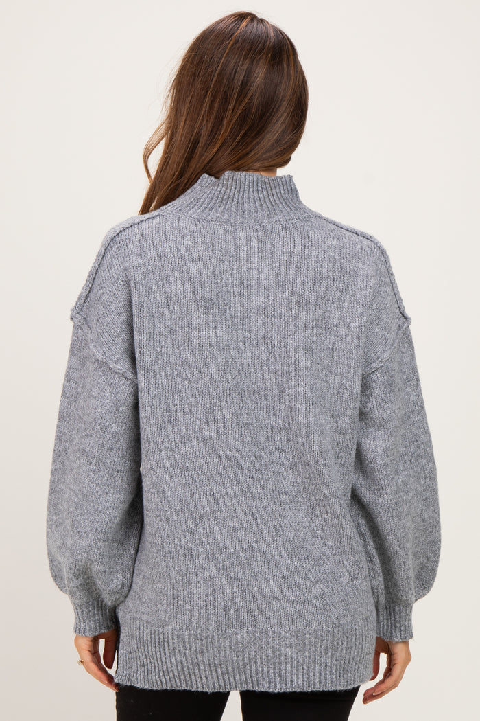 woman wearing a gray maternity sweater with a high neck and balloon sleeves, shown from the back