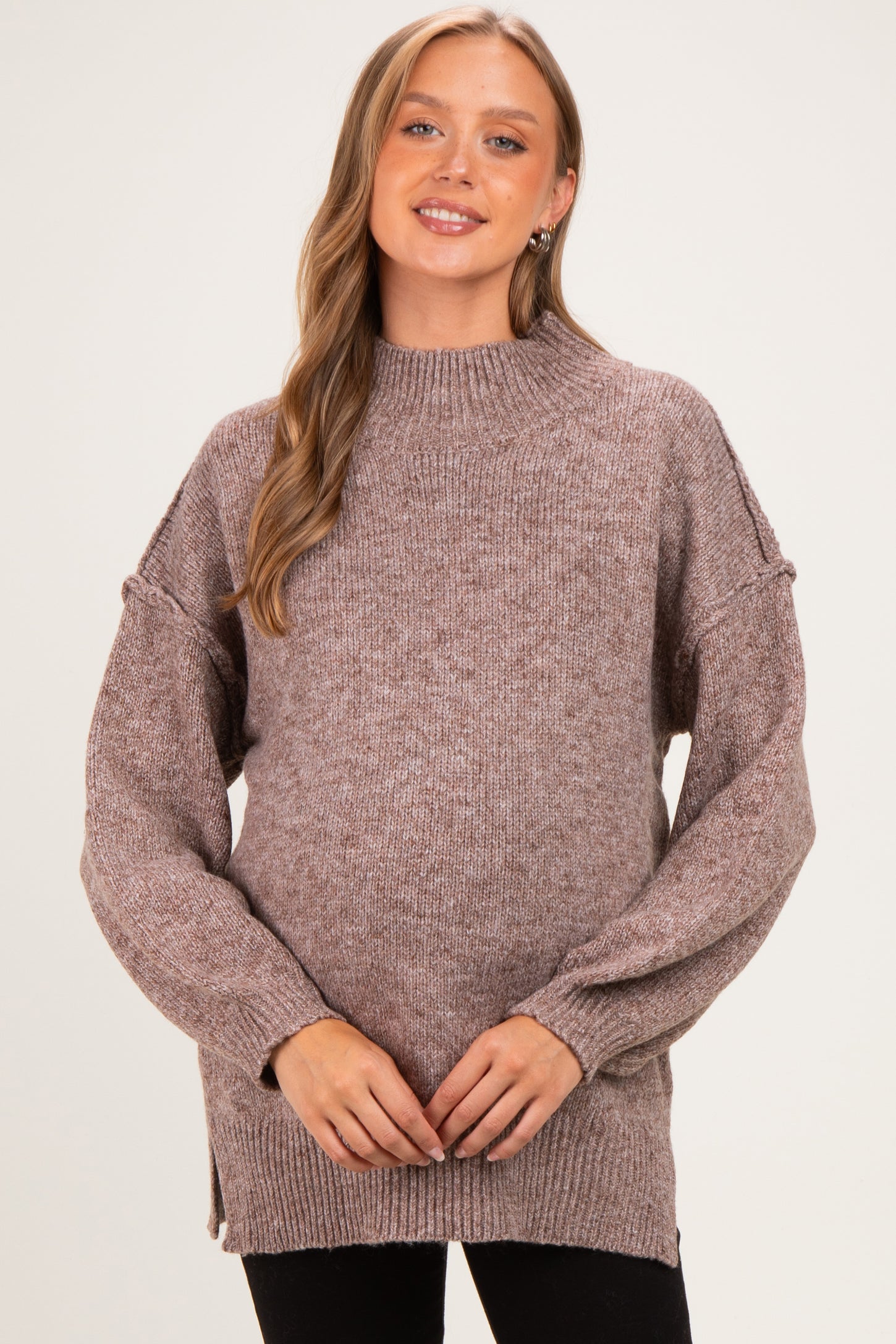 woman wearing a mauve maternity sweater with a high neck and balloon sleeves, showcasing her baby bump