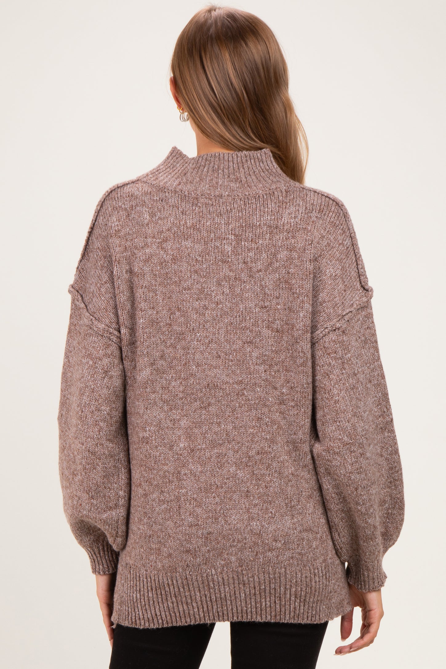 woman wearing a cozy brown maternity sweater with a high neck and balloon sleeves, showing a relaxed fit from the back