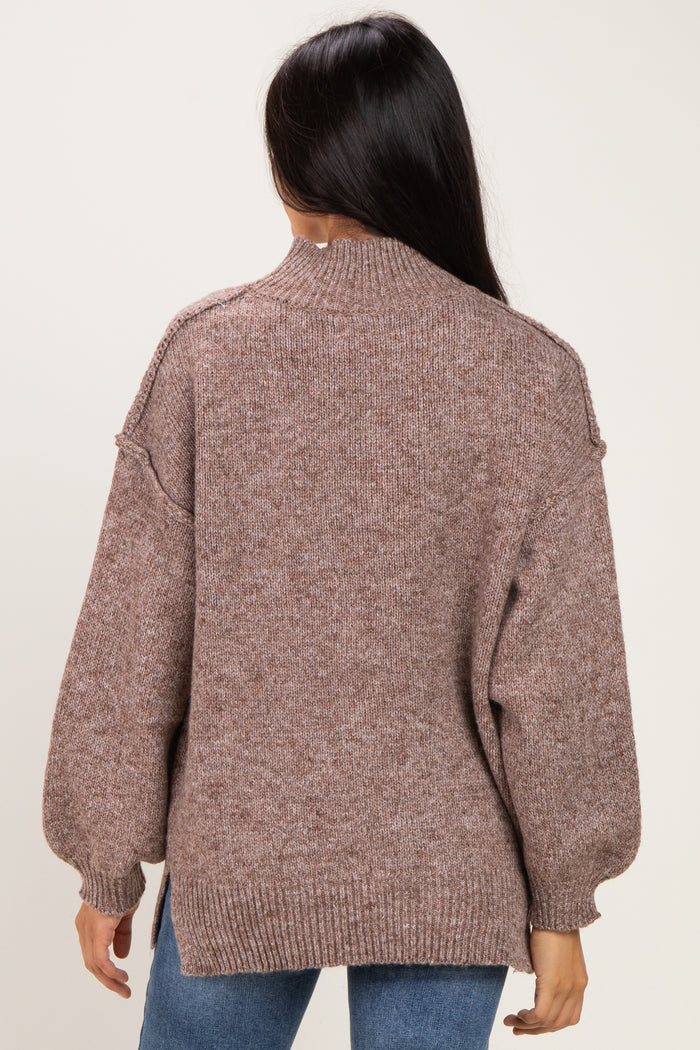 woman wearing a brown oversized knit sweater with a high neckline and balloon sleeves, viewed from the back