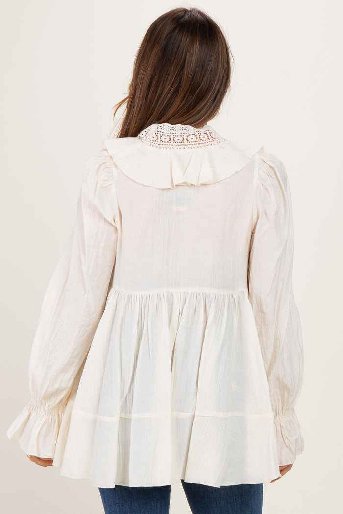 woman wearing a cream maternity top with a ruffled collar and long sleeves, showing a flowing silhouette from the back