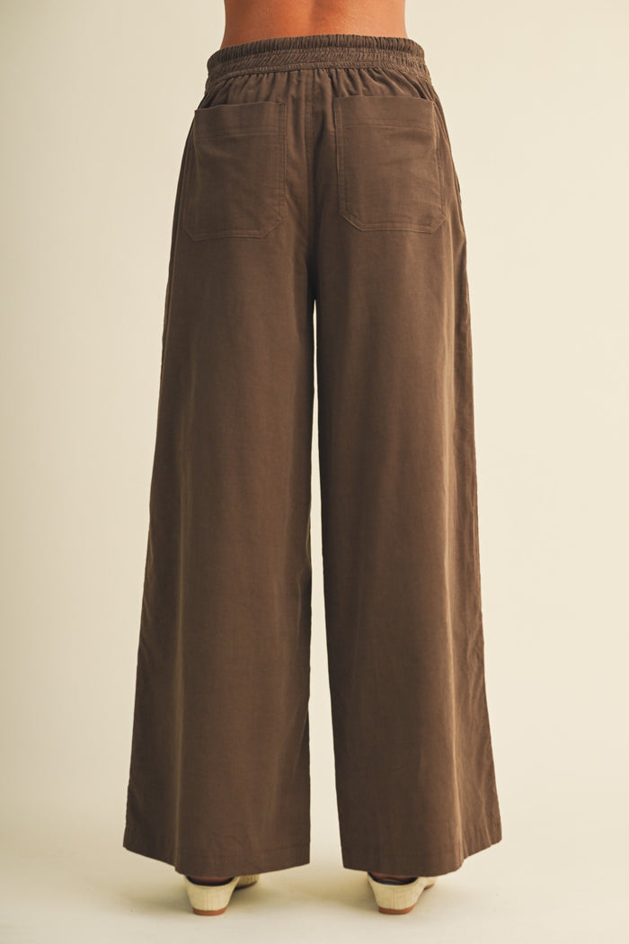 woman wearing brown wide-leg pants with an elastic waistband and two back pockets