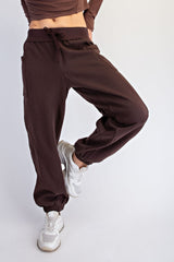 woman wearing dark brown jogger pants with pockets and elastic cuffs, paired with white sneakers