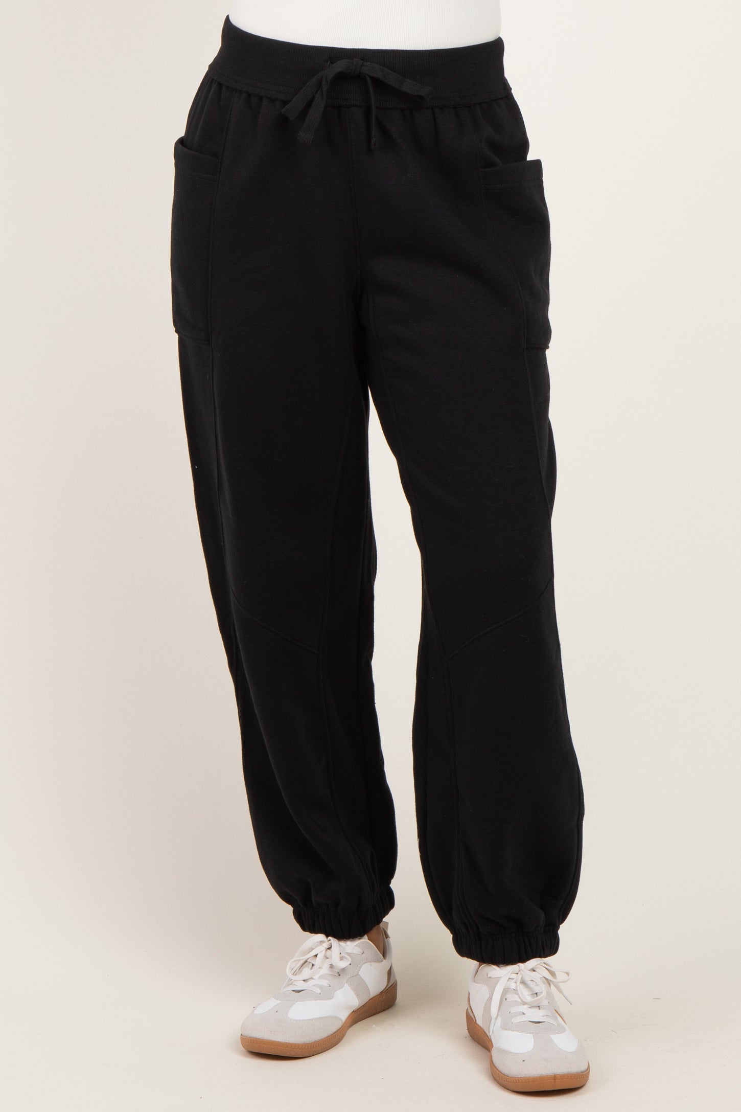 woman wearing black jogger pants with side pockets and elastic cuffs, paired with white sneakers