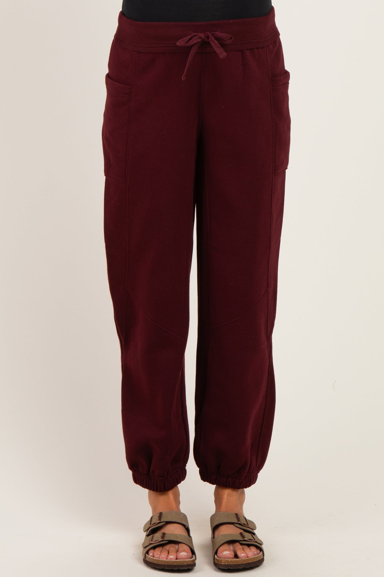 woman wearing maroon maternity sweatpants with side pockets and elastic cuffs