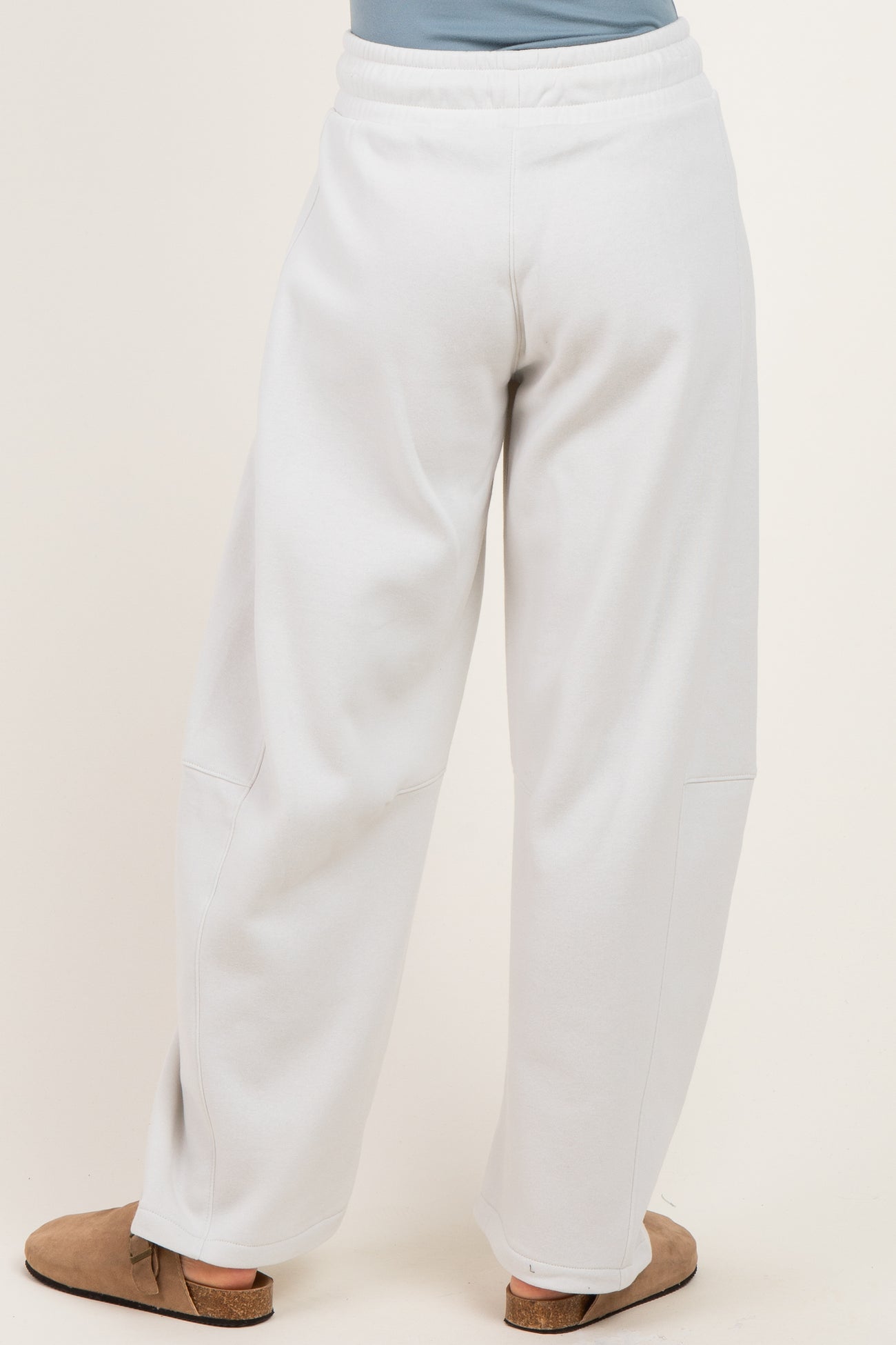 woman wearing light gray wide-leg sweatpants, shown from the back with an elastic waistband and side pockets