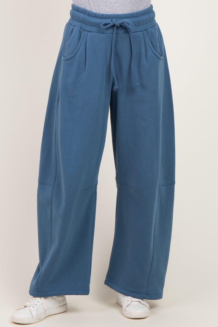 woman wearing blue wide-leg sweatpants with pockets and an elastic waistband, paired with white sneakers