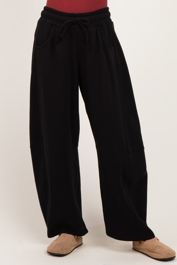 woman wearing black wide-leg sweatpants with a drawstring waist and side pockets
