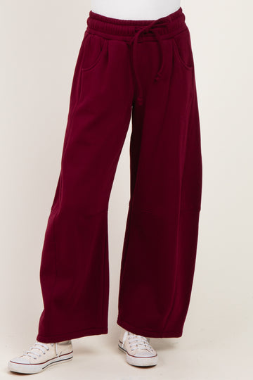 woman wearing burgundy wide-leg lounge pants with an elastic waistband and side pockets.