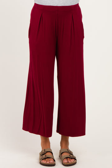 woman wearing a pair of burgundy maternity wide leg pants with pleat details