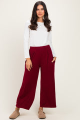 woman wearing a white long sleeve top and burgundy wide-leg pants with side pockets