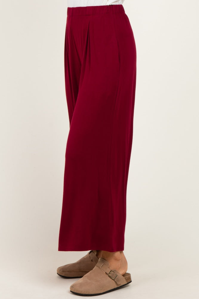 woman wearing burgundy wide leg pants with a pleated front and tan slip-on shoes