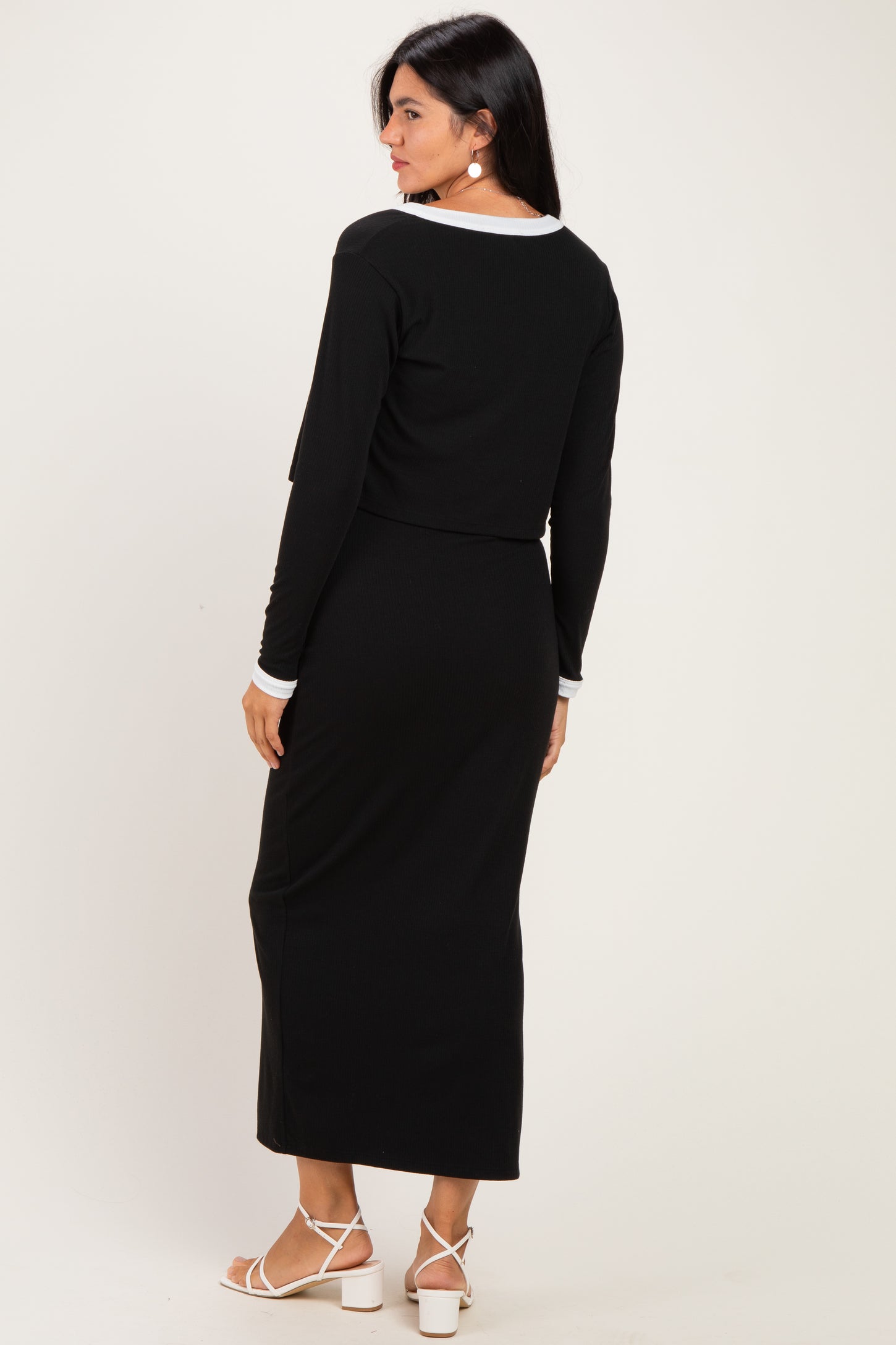 woman wearing a black long sleeve cropped top and matching maxi skirt, viewed from the back